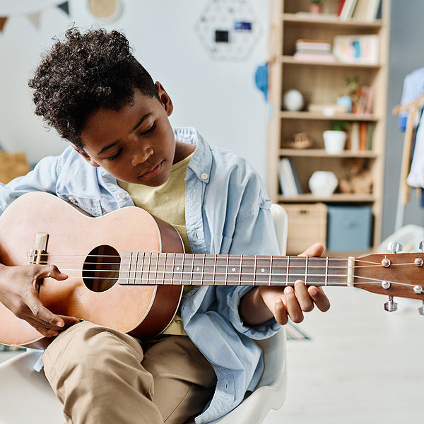 young boy playing guitar learning songs