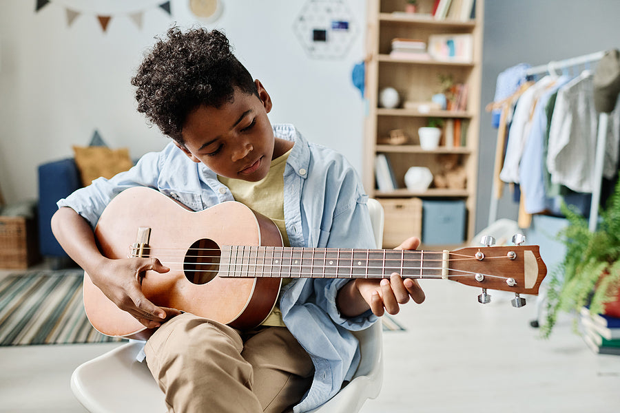 young boy playing guitar learning songs